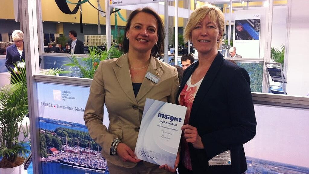 Anja Kron (LHG, re.) und Barbara Schwartz (LTM) mit der Auszeichnung auf der Kreuzfahrermesse in Miami. Foto: LHG
